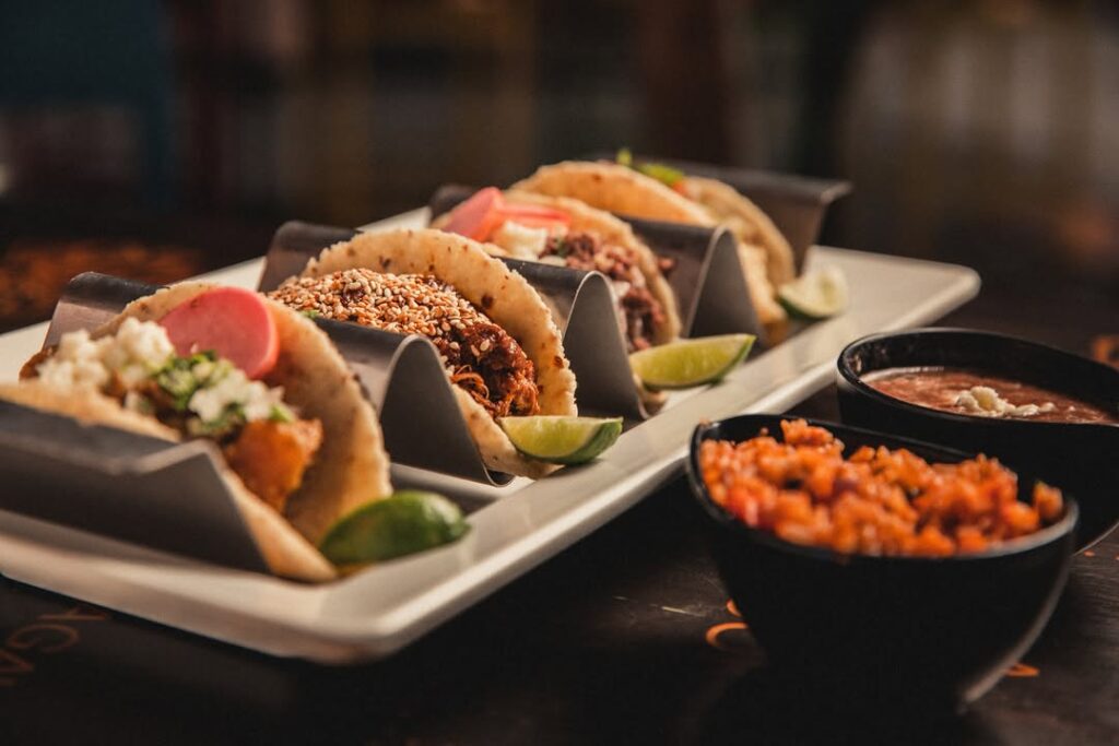 A Selection of tacos on a white plate with a side of salsa and tortilla soup from one of the best restaurants in nairobi.