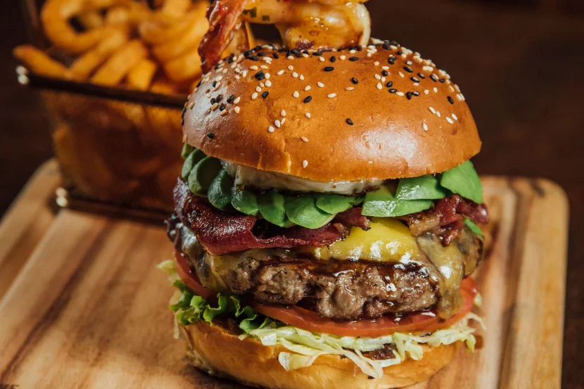 A juicy cheese burger with bacon lettuce tomatoes served on a wooden platter by one of the best grill restaurants in Nairobi. 