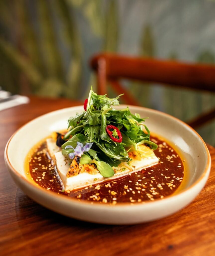 A slice of tofu douzed in an orange sauce and garnished with rocket and chillis at one of the best bistro restaurants in nairobi.